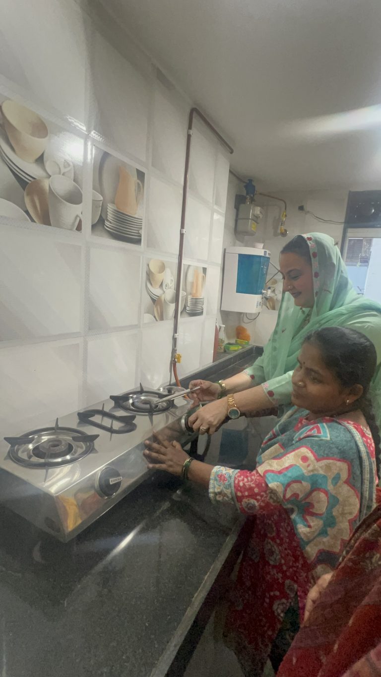 Two women stand together at a kitchen stove, with their hands near the burner controls.