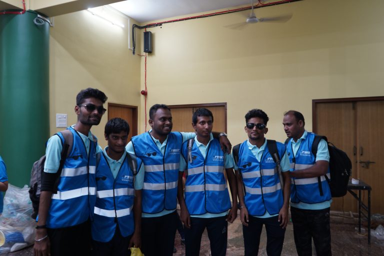 Goalball participants wearing blue reflective jackets stand together at the championship.