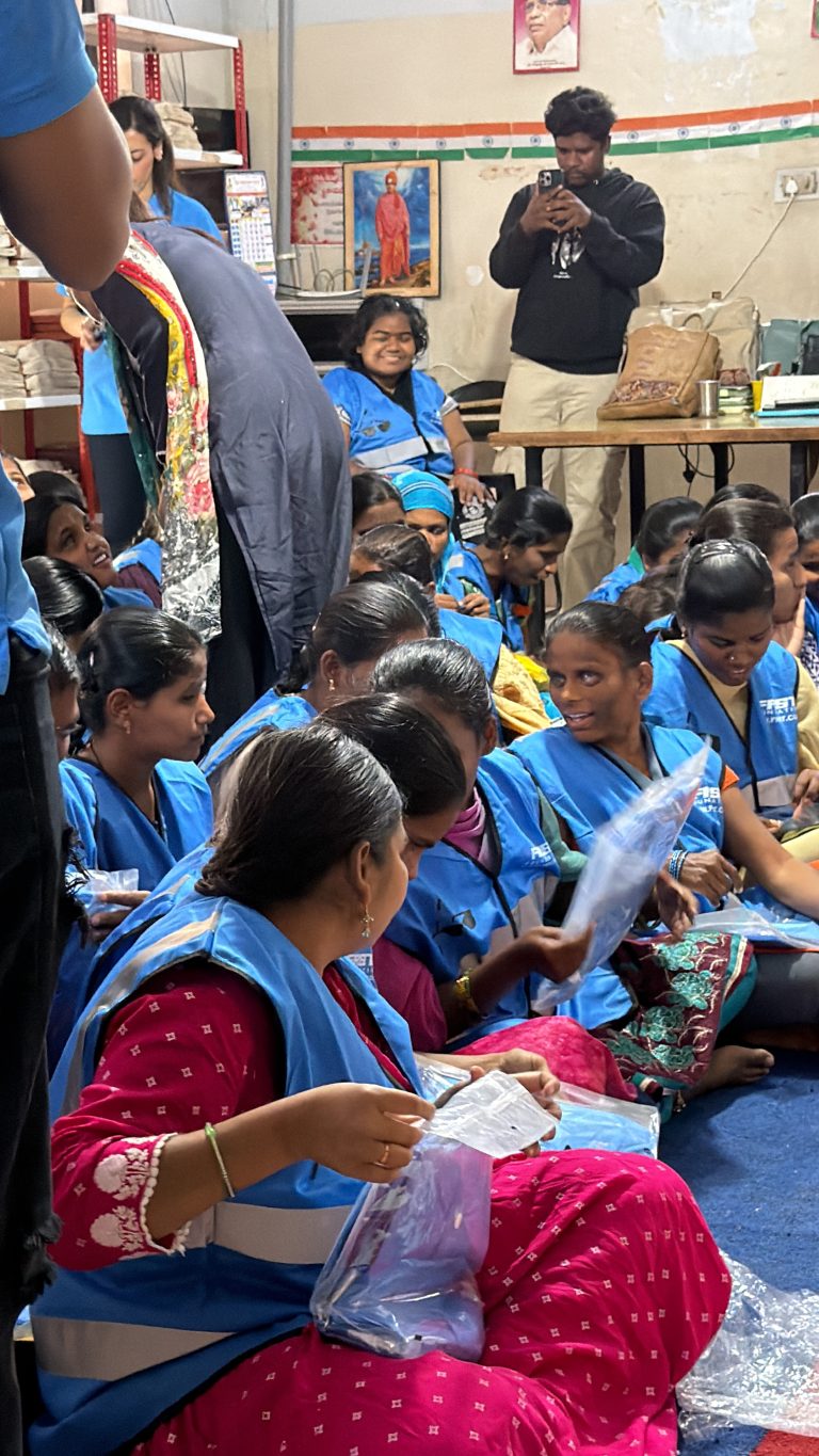 Girls wearing blue reflective jackets gather during the FRST community visit in Hyderabad.