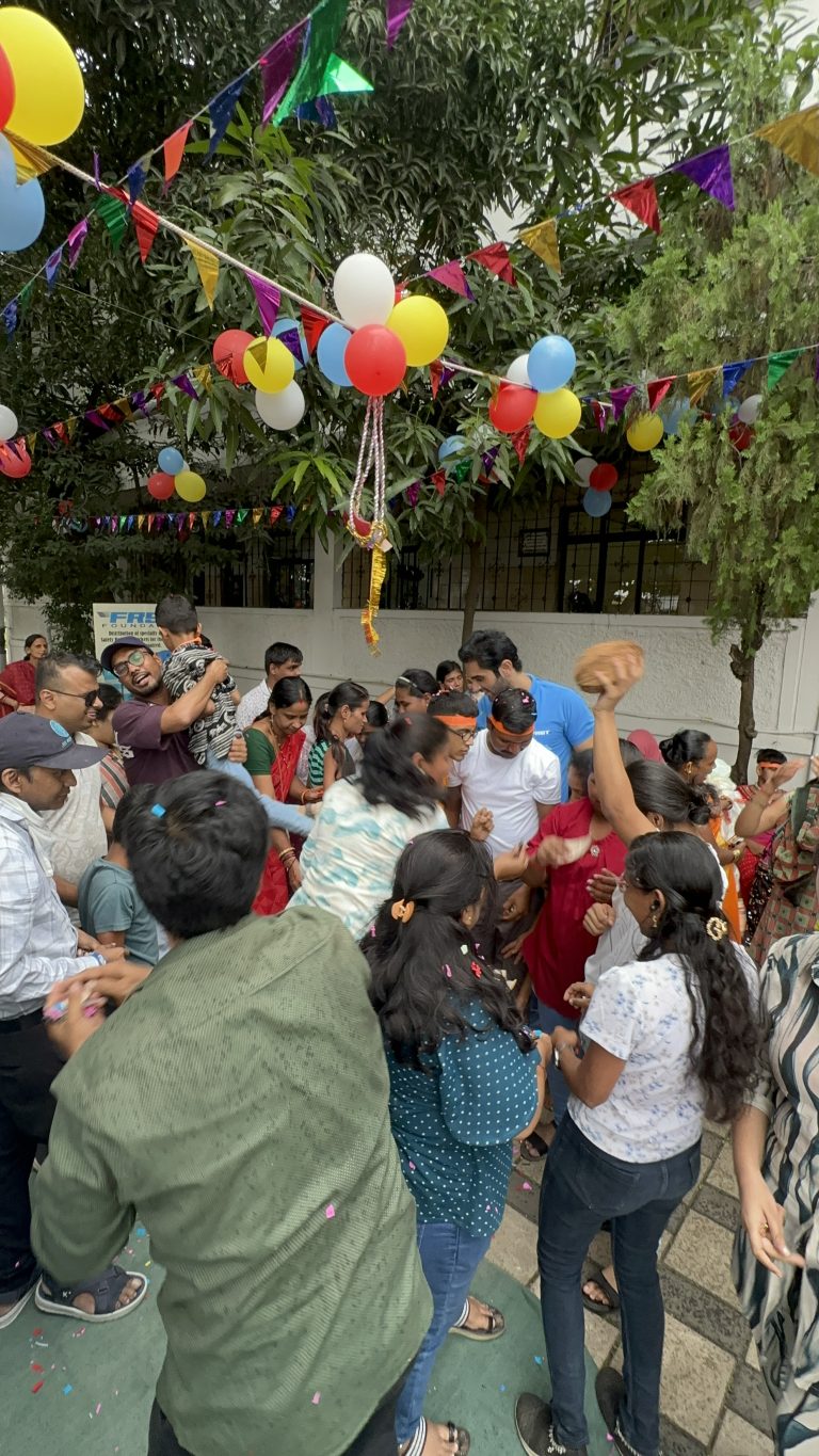 Participants celebrate Janmashtami together beneath a decorated handi at PBMA.