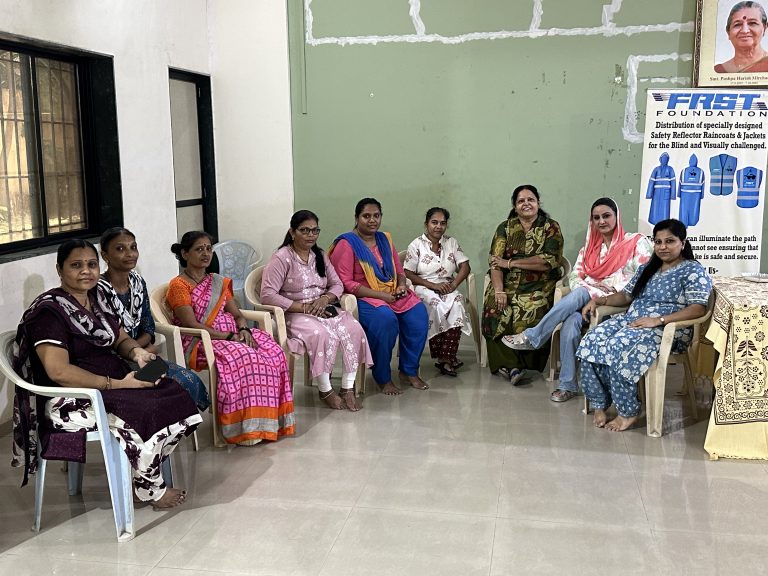 Women gather together beside the FRST safety-gear banner during the Kumudben birthday visit.