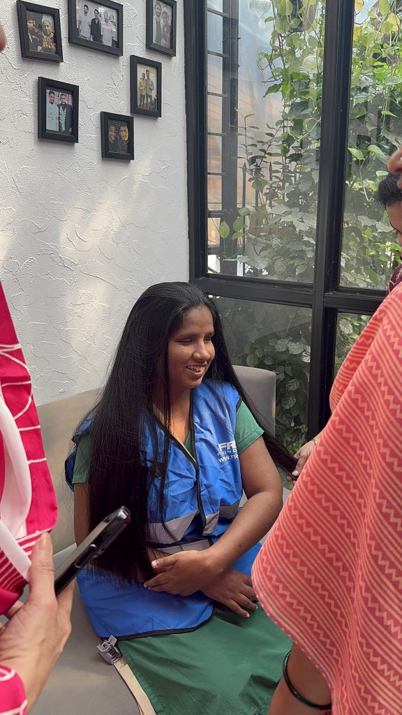 A woman smiles during a salon visit with other participants nearby.